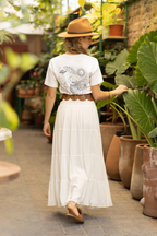 Person wearing a white Beautiful Minds graphic tee featuring celestial artwork with stars, planets, a crescent moon and a profile illustration on the back.