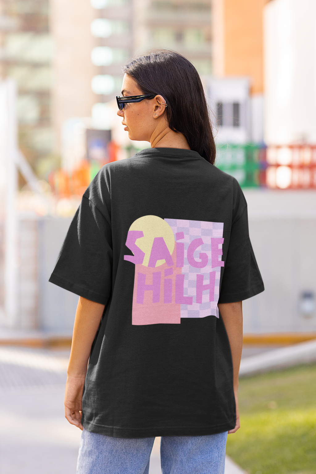 Woman wearing an oversized T-shirt facing away from the camera with large pink and purple pastel art on the back of the t-shirt