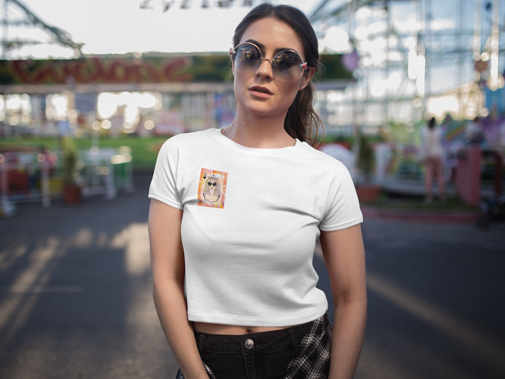 Person wearing a white Queen of Your Own Story crop tee featuring original artwork of a crowned character with sunglasses on the front chest.