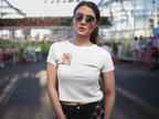 Person wearing a white Queen of Your Own Story crop tee featuring original artwork of a crowned character with sunglasses on the front chest.