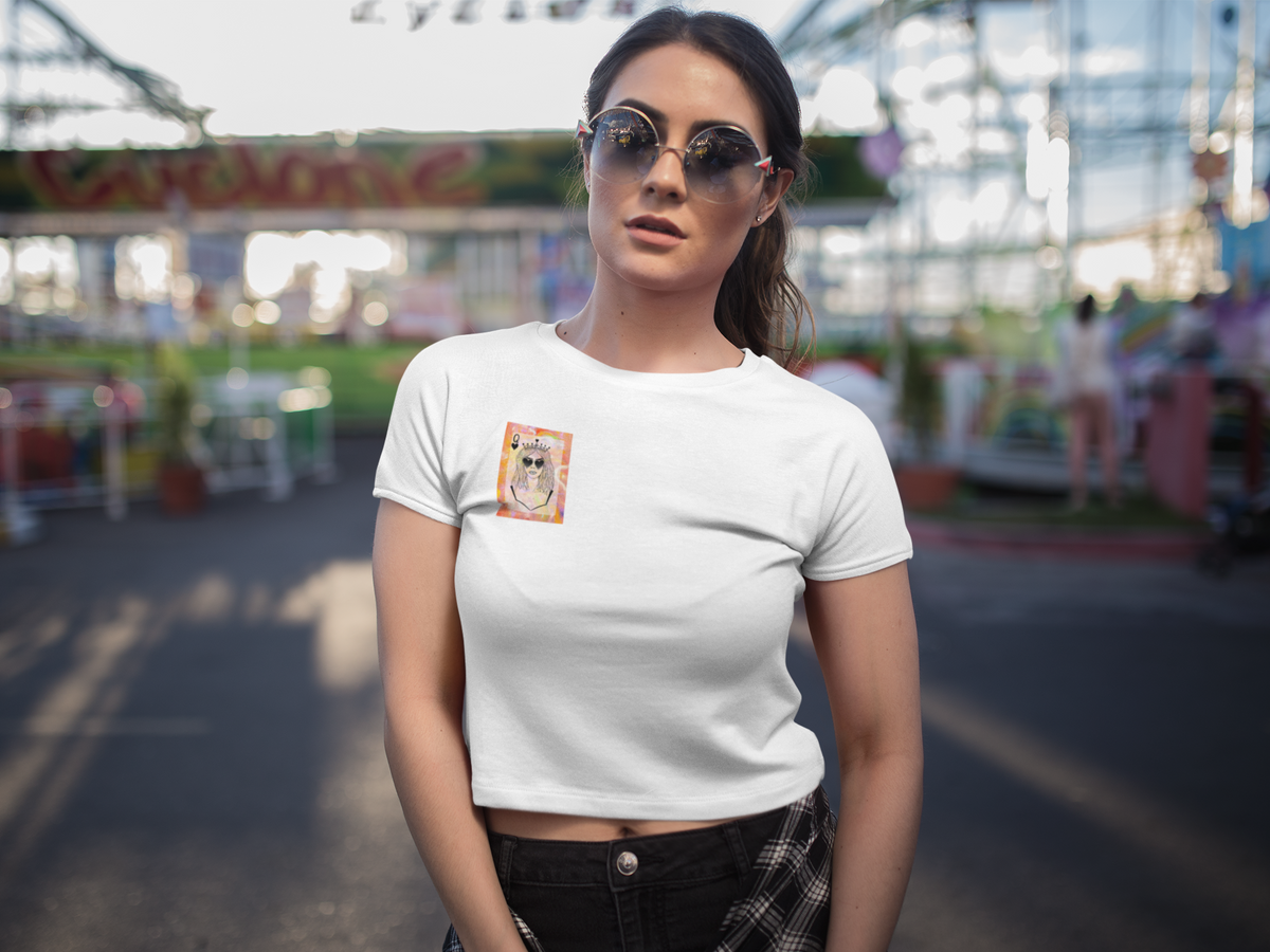 Person wearing a white Queen of Your Own Story crop tee featuring original artwork of a crowned character with sunglasses on the front chest.