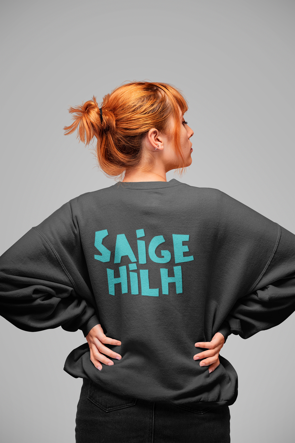 model wearing a black crewneck sweatshirt with SAIGE HILH in big blue text on the back