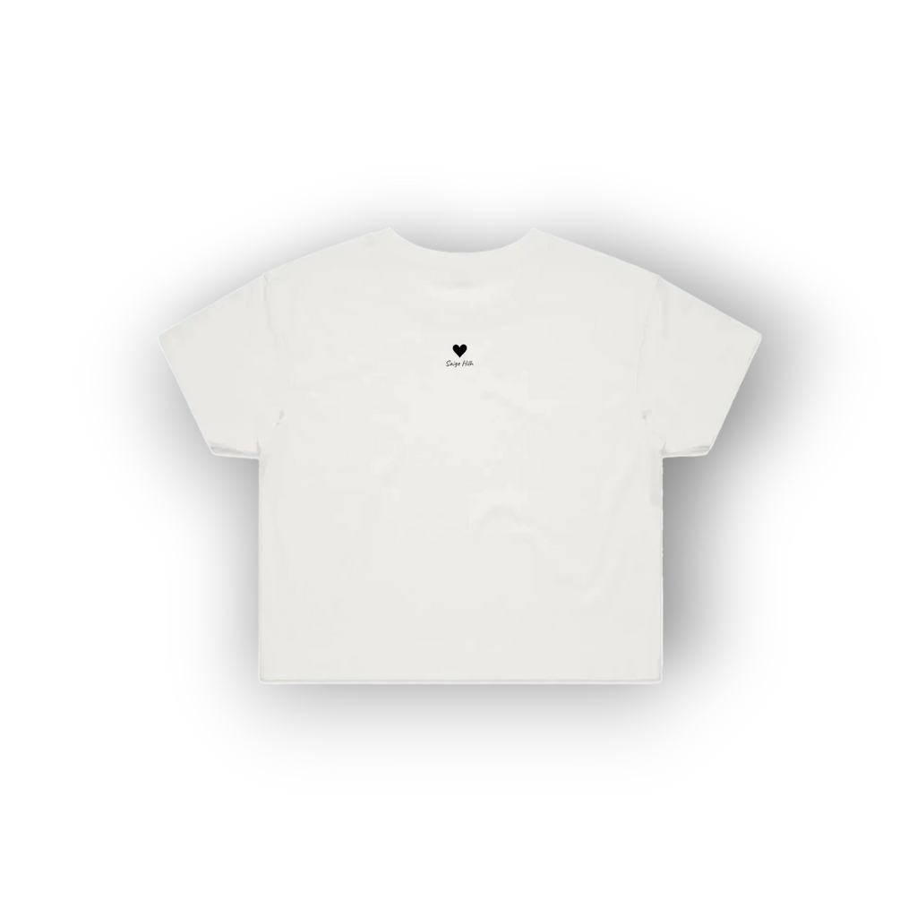 A white short-sleeve crop top t-shirt with a small pink heart and flower graphic on the upper chest, displayed against a clean white background with a soft drop shadow.