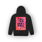 A black pullover hoodie shown from the back, featuring a large square graphic print with the text 'THIS TOO SHALL PASS' in dark blue lettering over a pink and orange floral background.