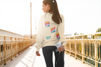 women stretching for a run with a beige hoodie shown from the back, featuring three colourful retro wavy graphic squares and the text 'SAIGE HILH' in teal on the back.